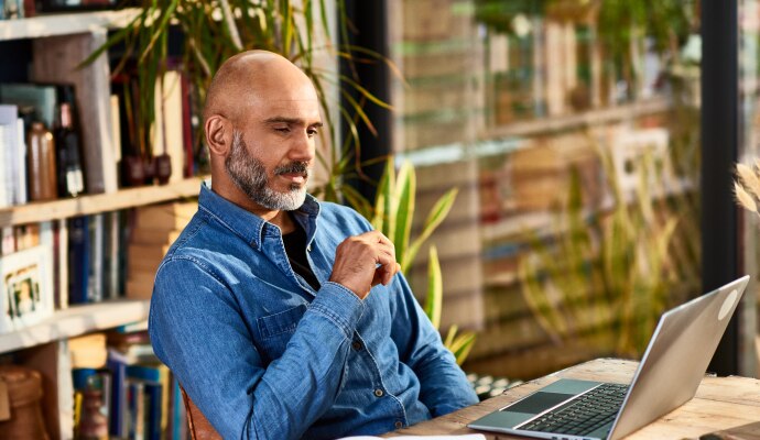 Hombre sentado a un escritorio mirando una computadora portátil